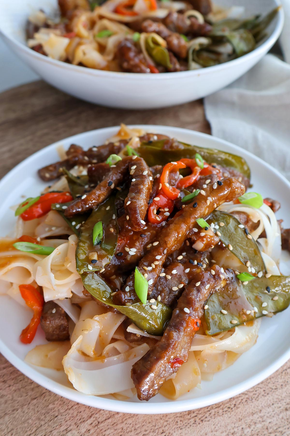 Plateful of beef strips and veggies over noodles.