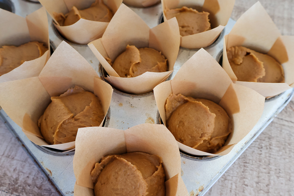 Pumpkin muffin batter in lined muffin tin.