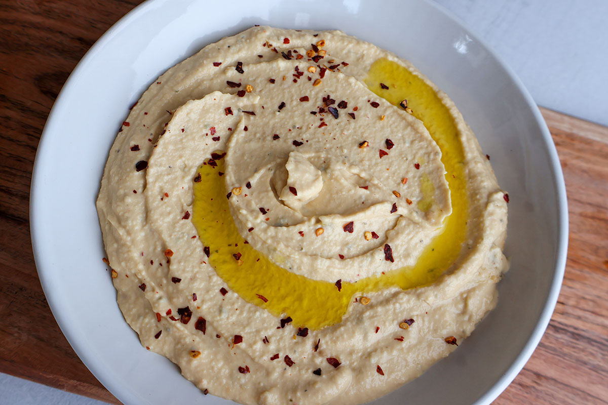 Bowlful of hummus topped with olive oil and red pepper flakes.