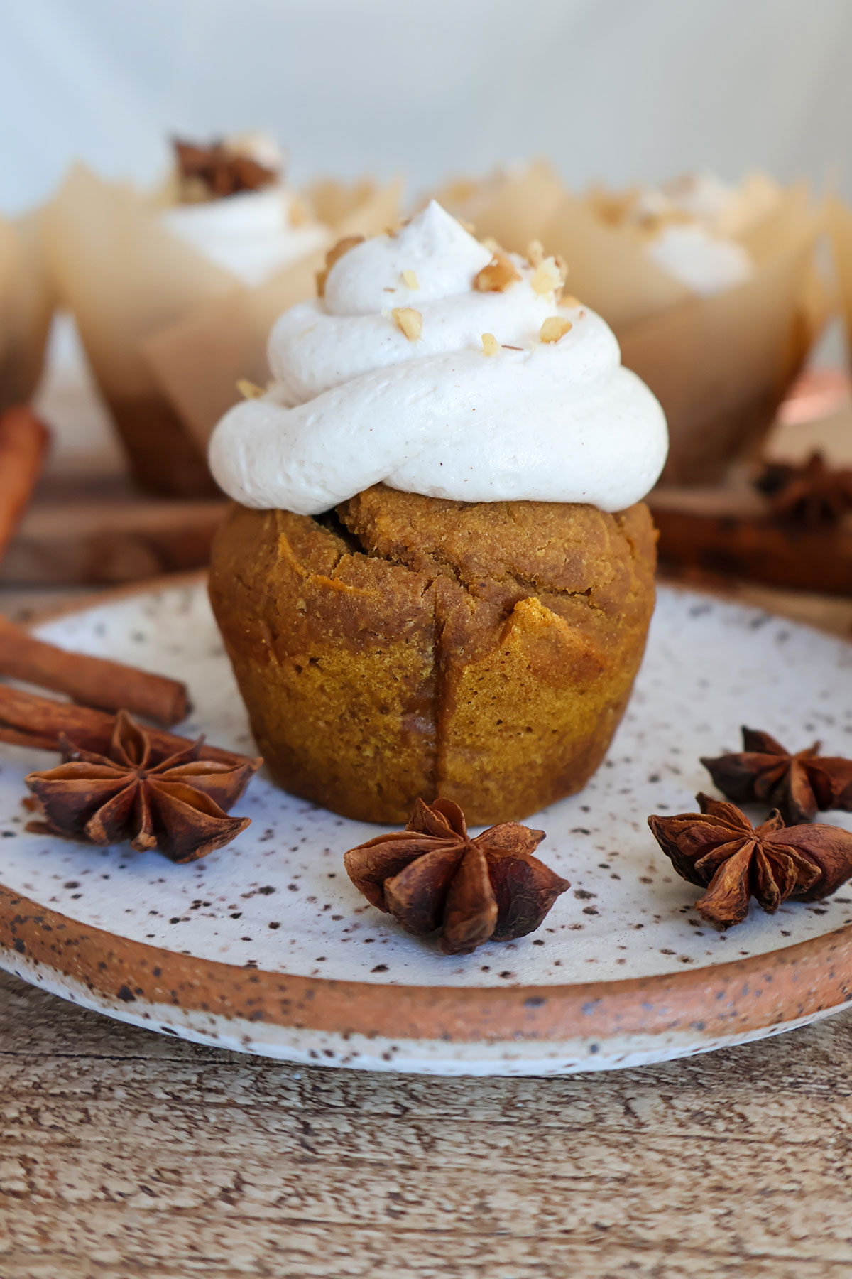 Plate with cream cheese frosted pumpkin muffin.