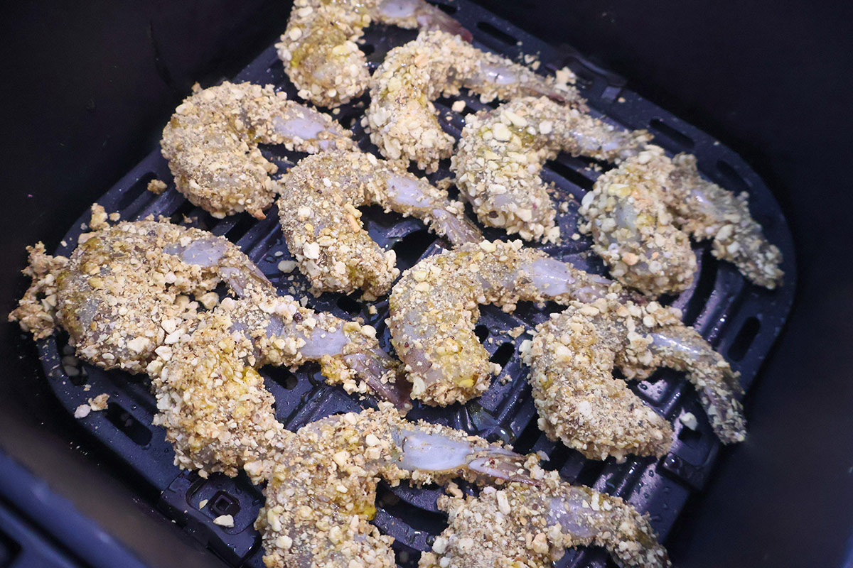 Uncooked breaded shrimp in air fryer basket.