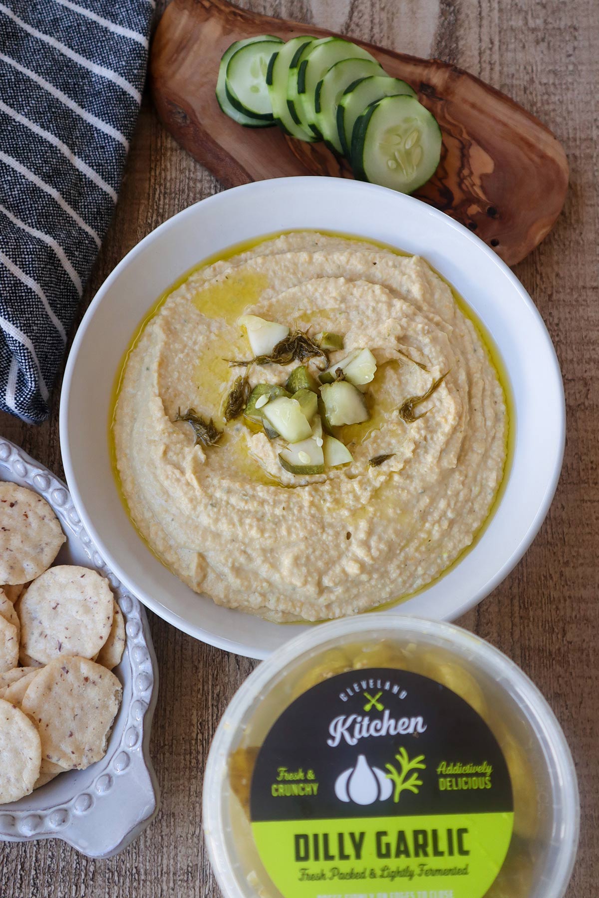Overhead shot of bowlful of hummus next to pickle container.
