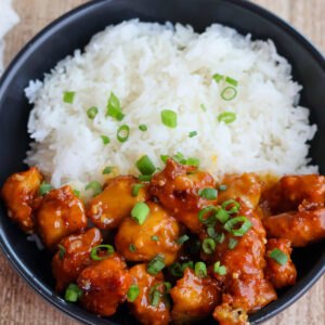 Overhead shot of bowlful of orange chicken with white rice.