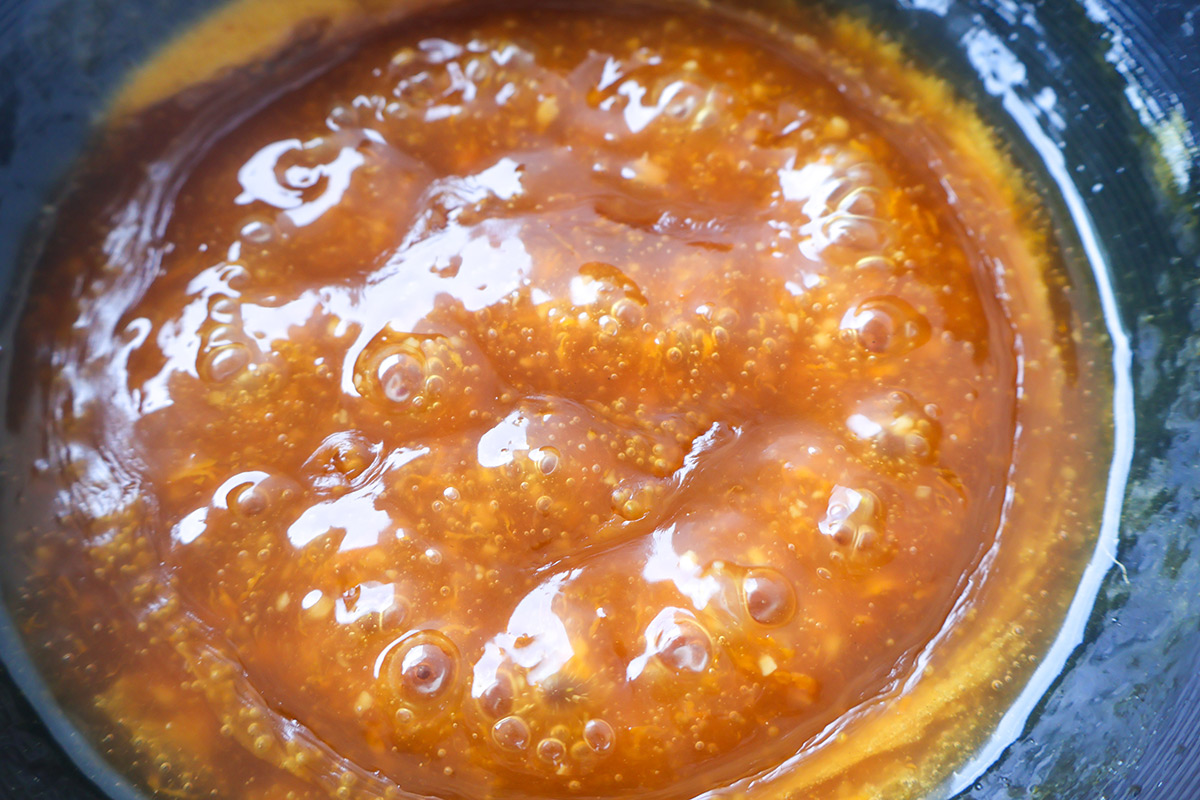 Wok full of orange chicken sauce.