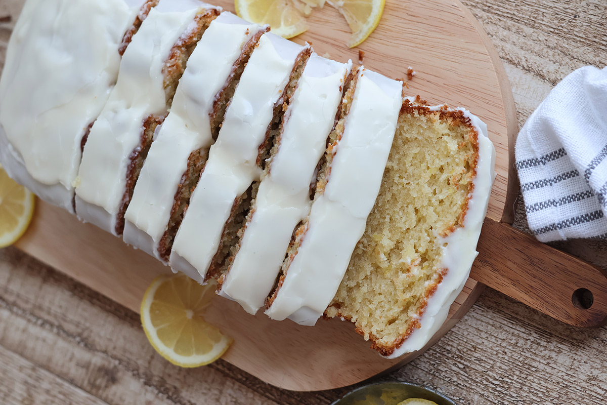 An overhead shot of a sliced frosted lemon loaf cake. 