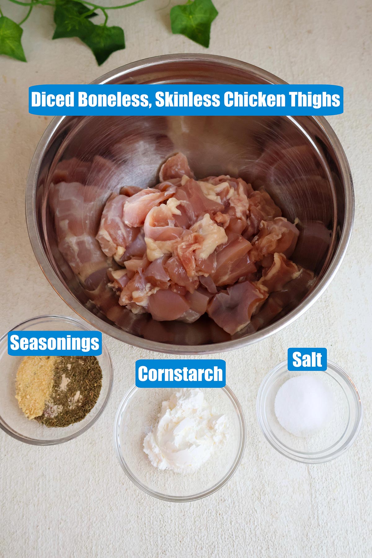 Diced chicken thighs, cornstarch, salt, and seasoning blend in individual bowls.