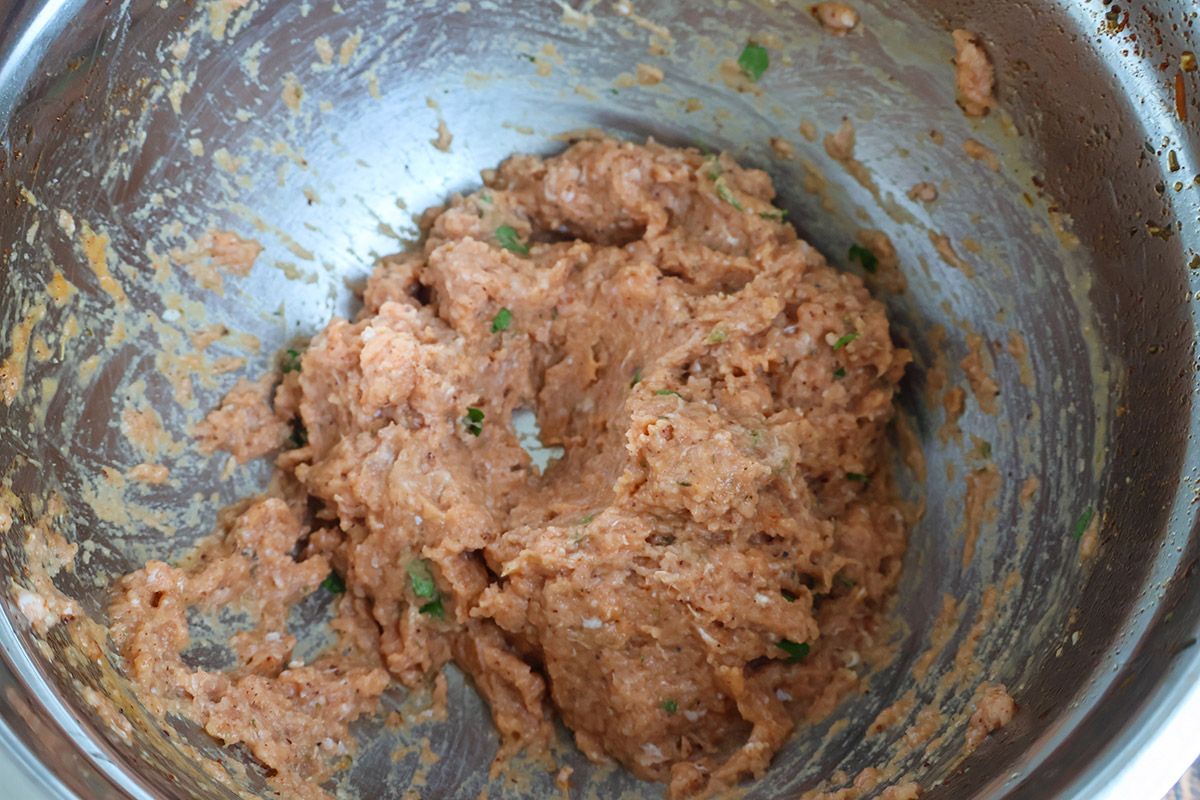 Turkey meatball mixture in a metal mixing bowl.
