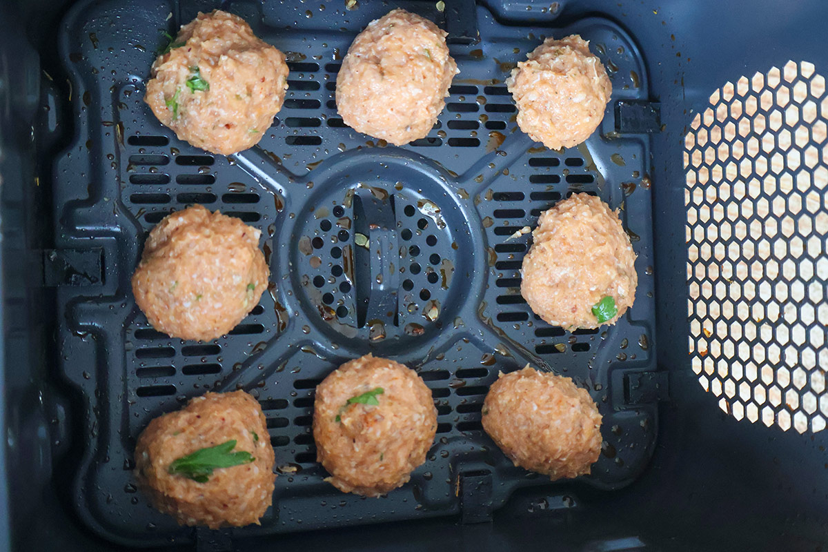 Eight turkey meaballs in an air fryer basket. 