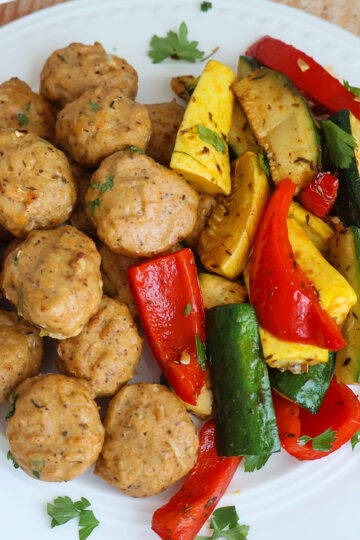 Golden meatballs with bell peppers on a white plate.