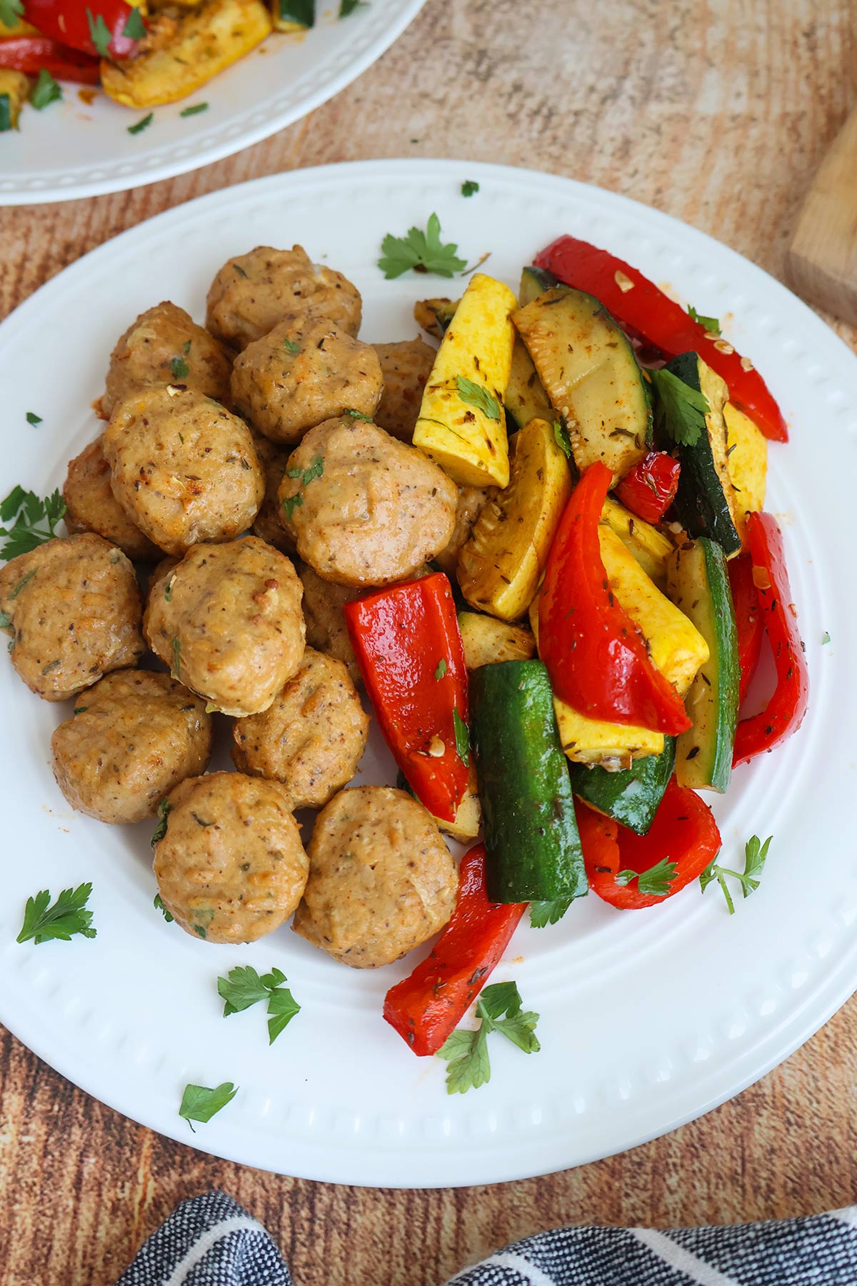 Golden meatballs with peppers on a white plate.