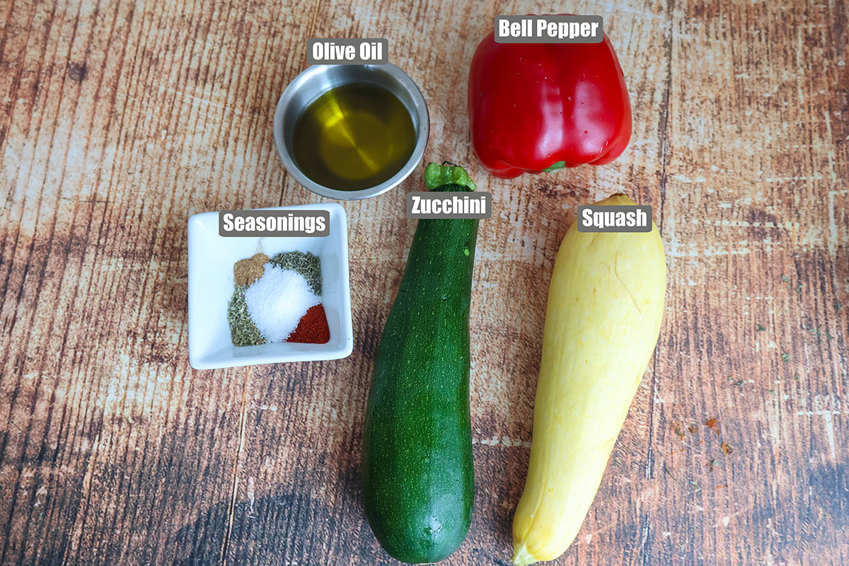 A bell pepper, zuchini, and squash next to bowls of oil and seasonings.