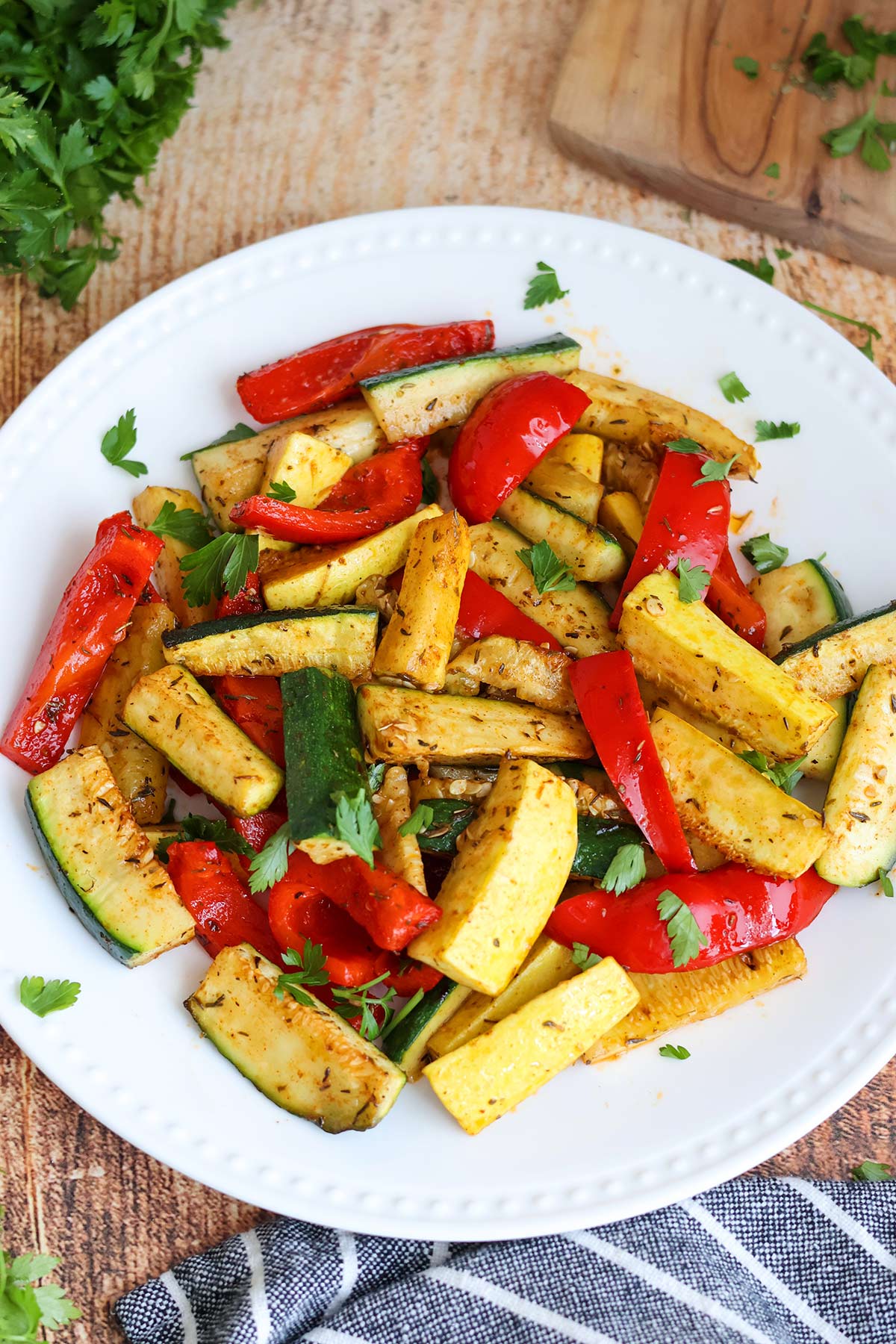 Sliced zucchini, squash, and bell peppers on a white plate.