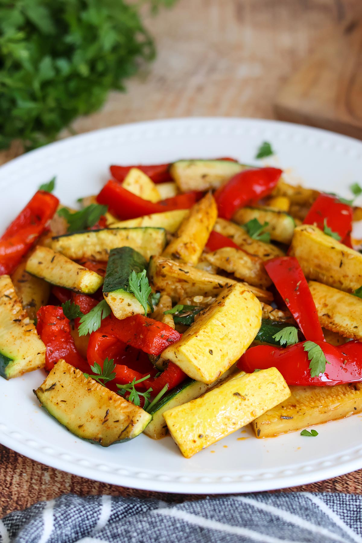 Seasoned, cooked zucchini, squash, and bell pepper strips on a white plate.