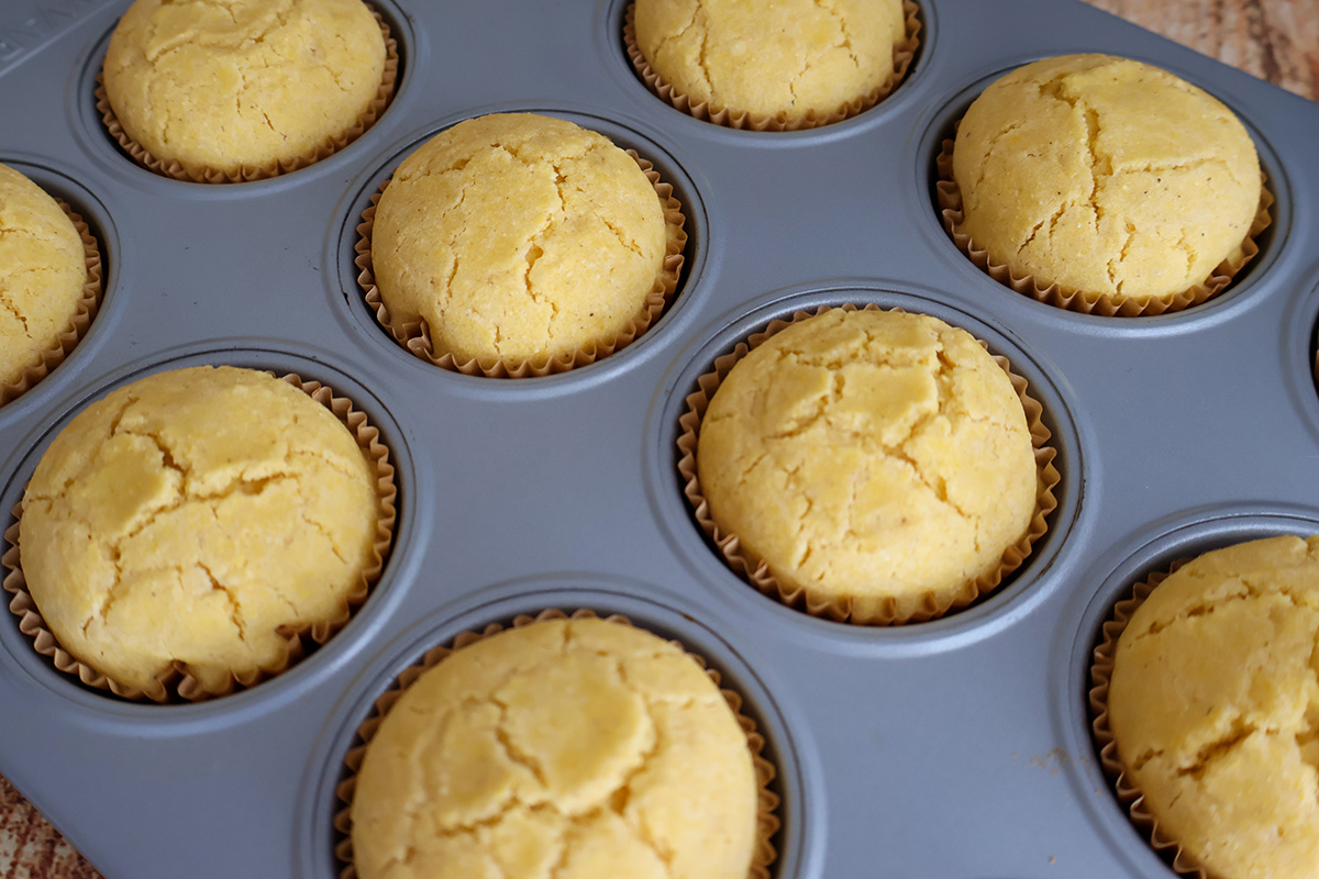 A 12-count muffin tin with baked corn muffins. 