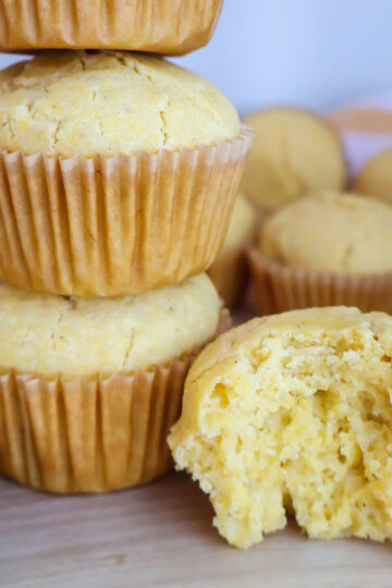 A stack of two corn muffins next to half of a corn muffin.