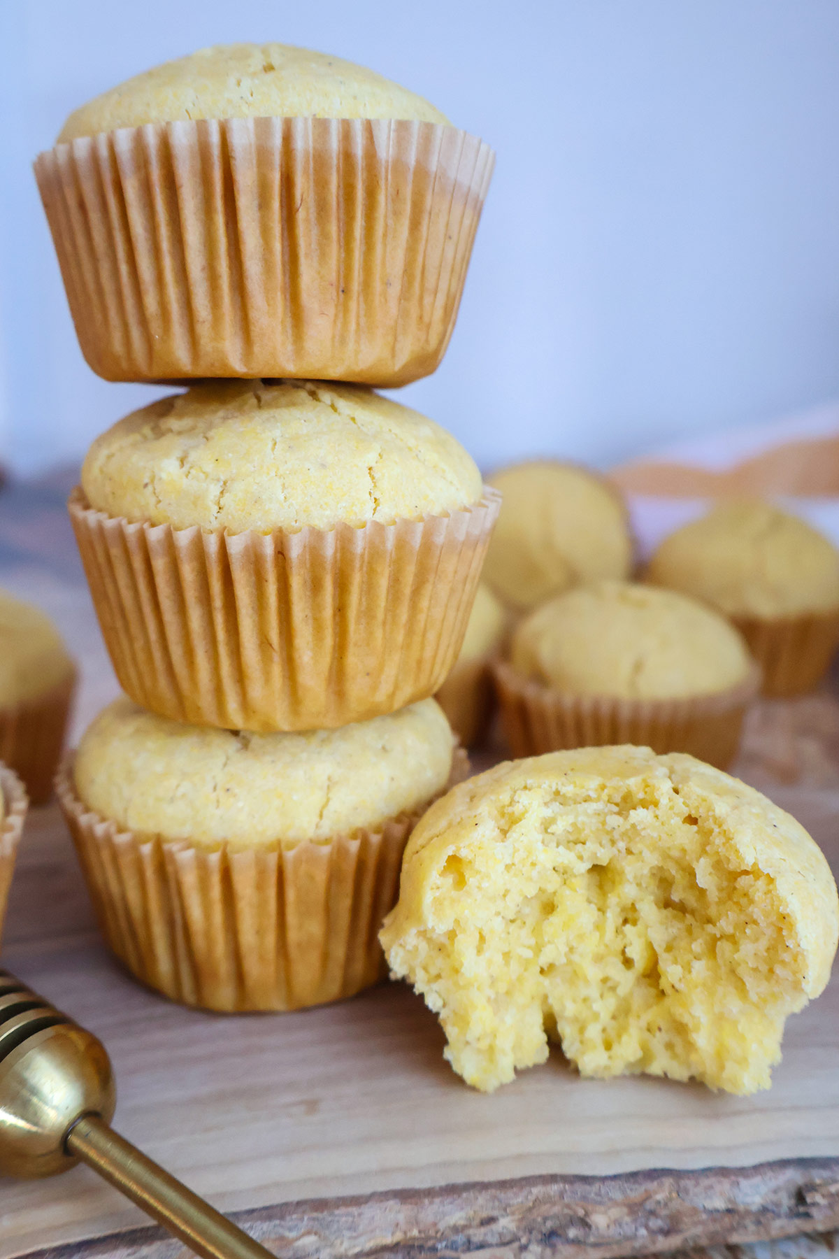 A stack of three corn muffins beside a corn muffin with a bite removed.