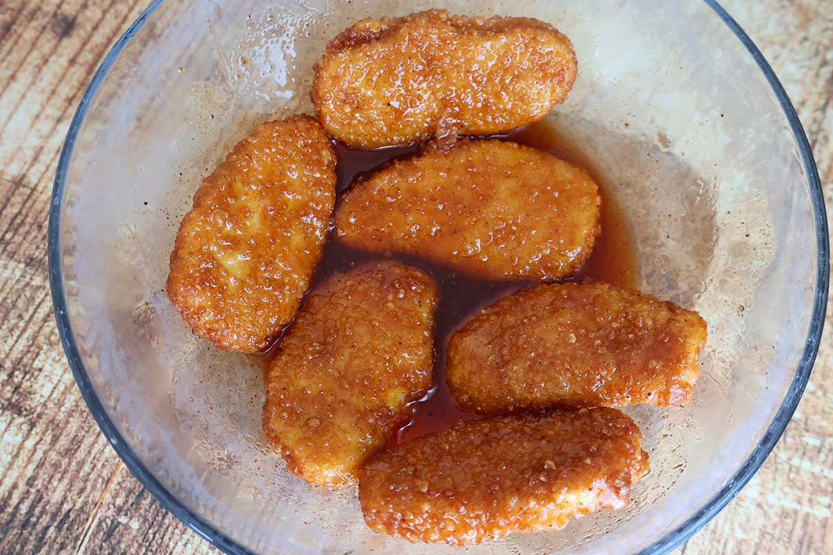 Six air-fried chicken tenders and hot honey sauce in a glass bowl.