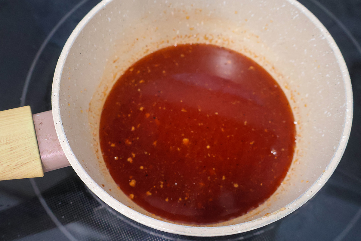 Hot honey sauce in a white enameled saucepan.
