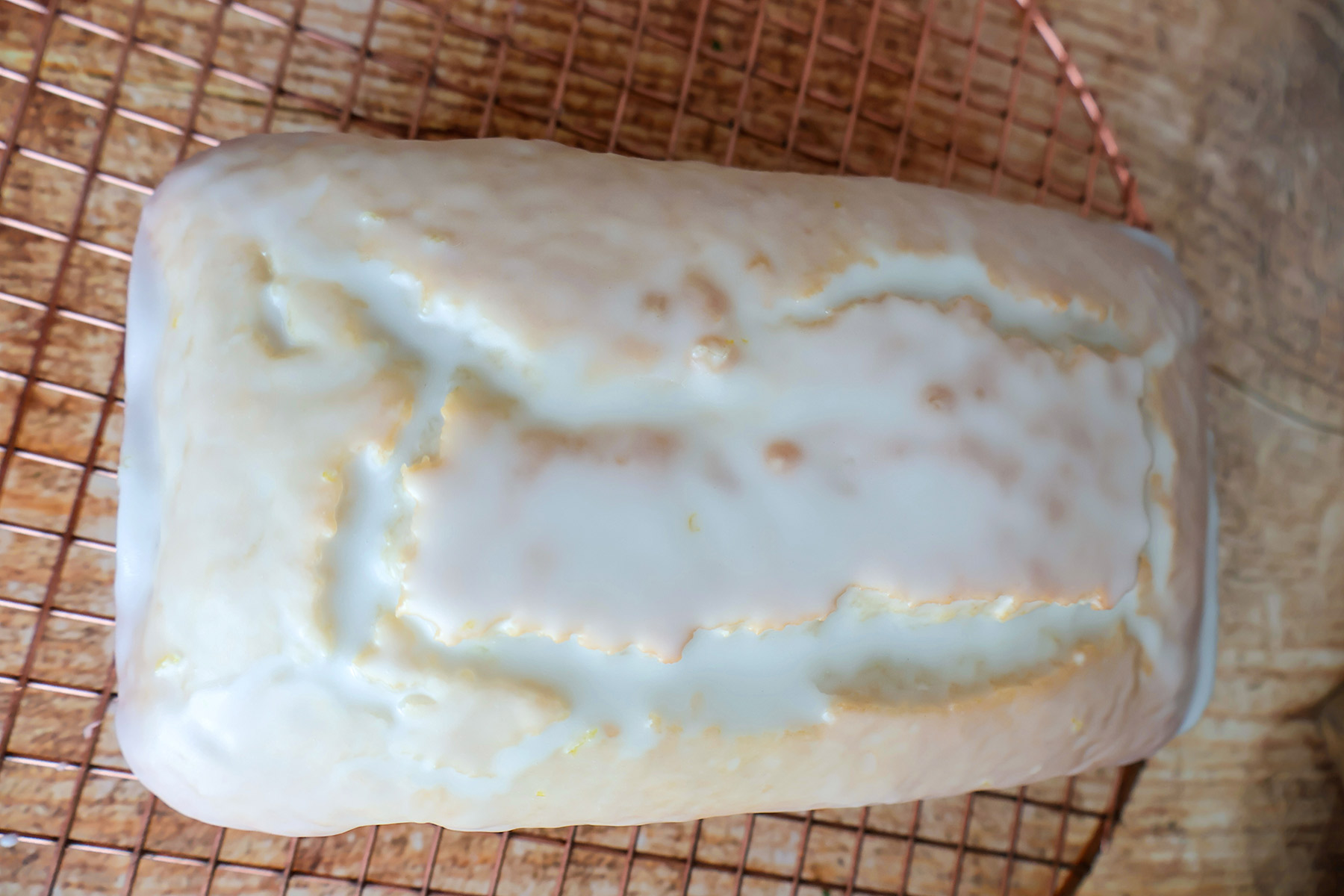 Frosted lemon loaf cake on a wooden board.