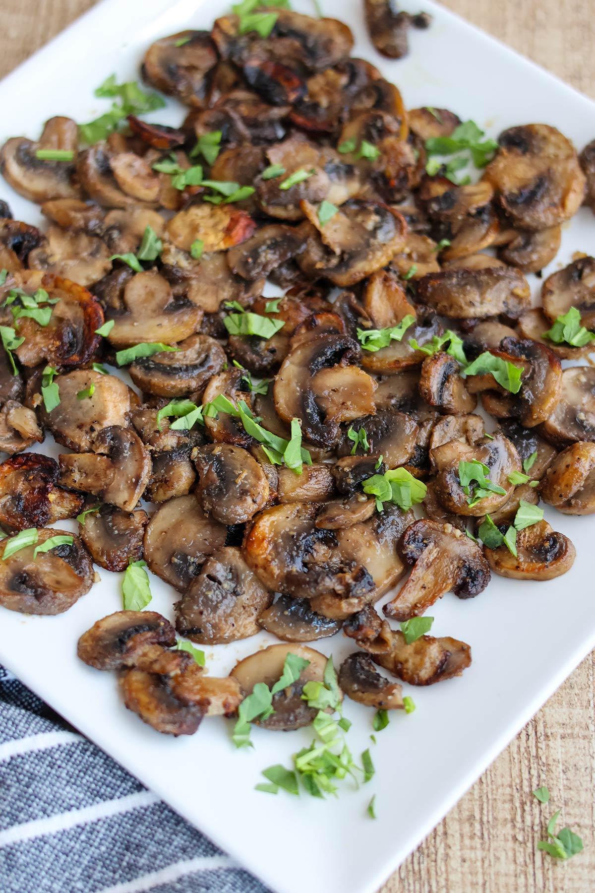 A white plate full of air fried mushroom slices.