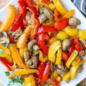 Mushrooms and red, yellow, and orange bell peppers on a white plate.