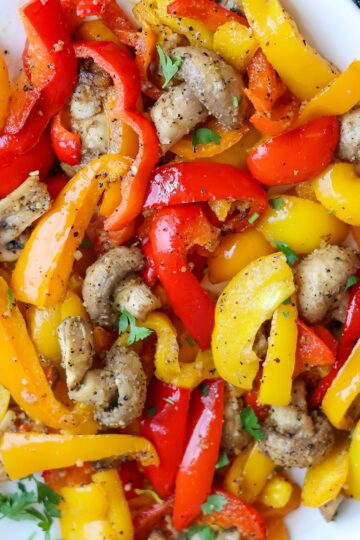 Mushrooms and red, yellow, and orange bell peppers on a white plate.