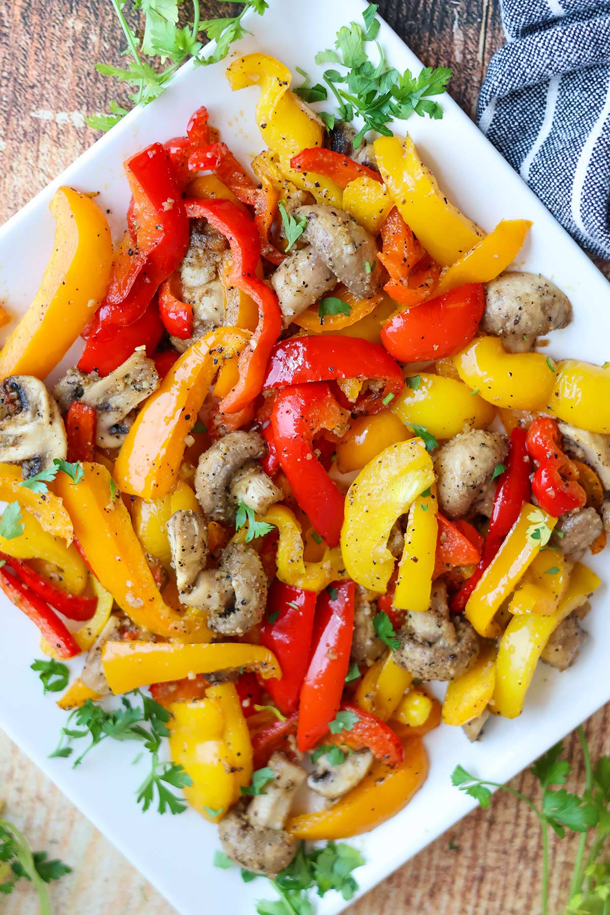 Mushrooms and red, yellow, and orange bell peppers on a white plate.