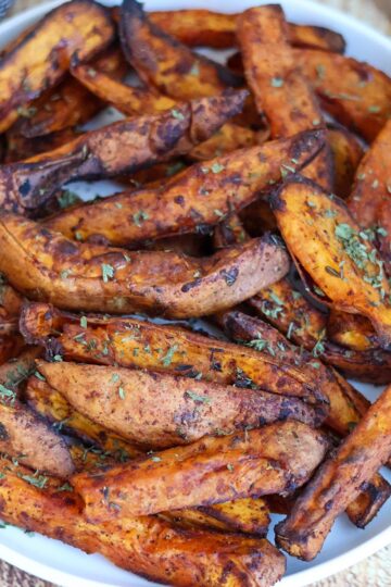 A white bowl filled with crispy sweet potato wedges.