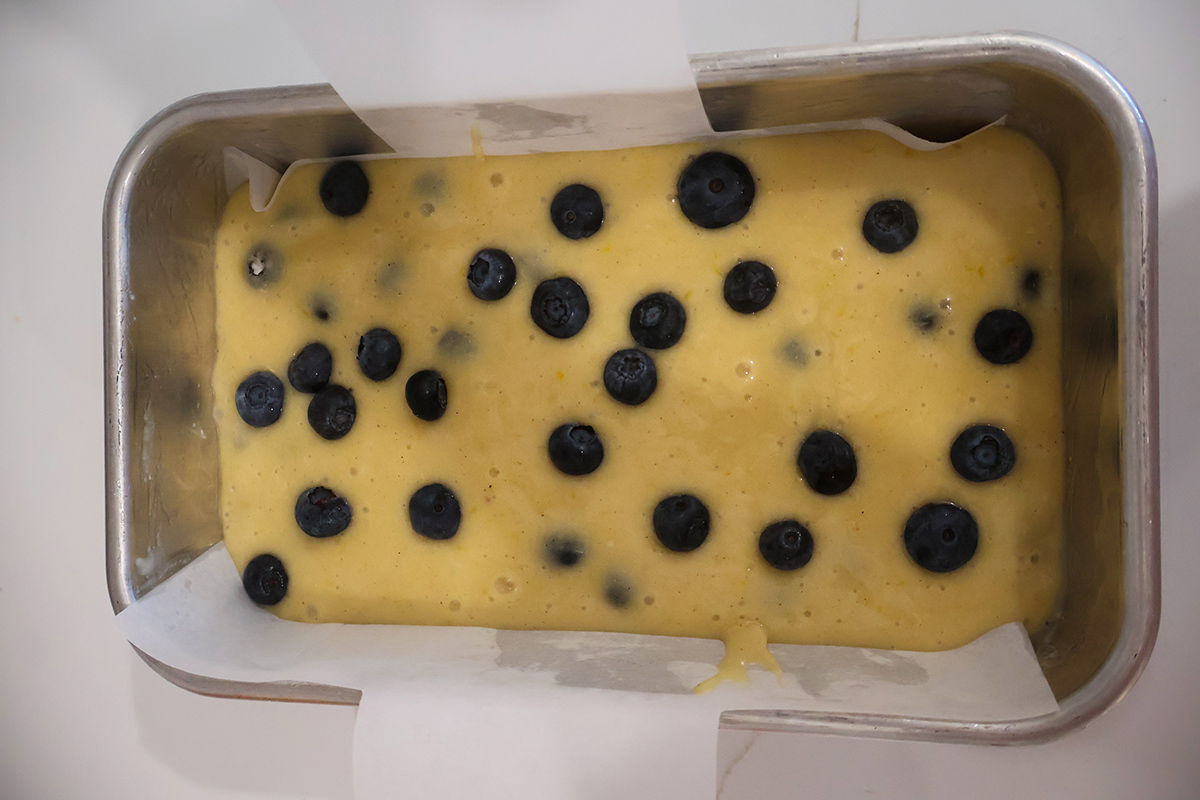 Blueberry loaf batter in a loaf pan lined with parchment paper.