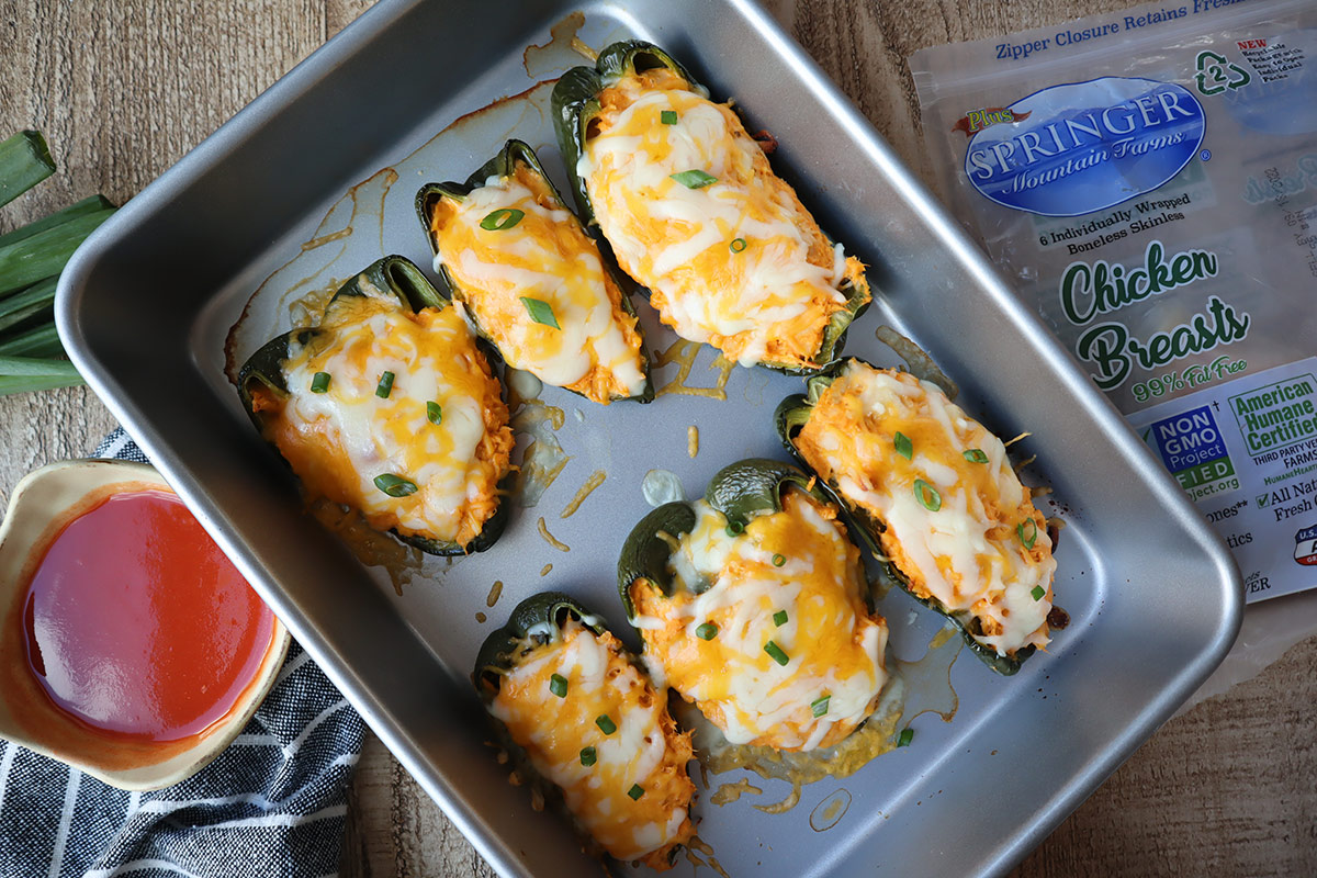 Baked stuffed poblano peppers in a baking pan.