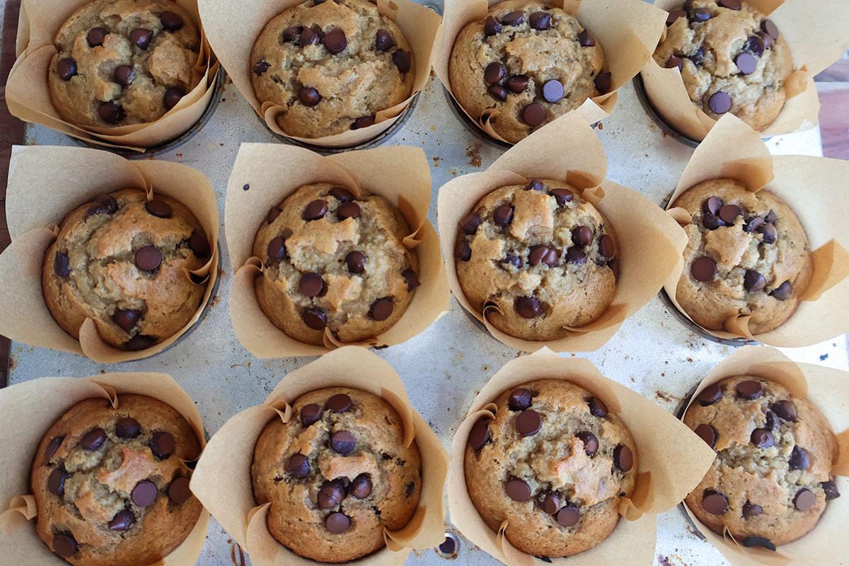 Twelve baked banana muffins in a muffin tin.