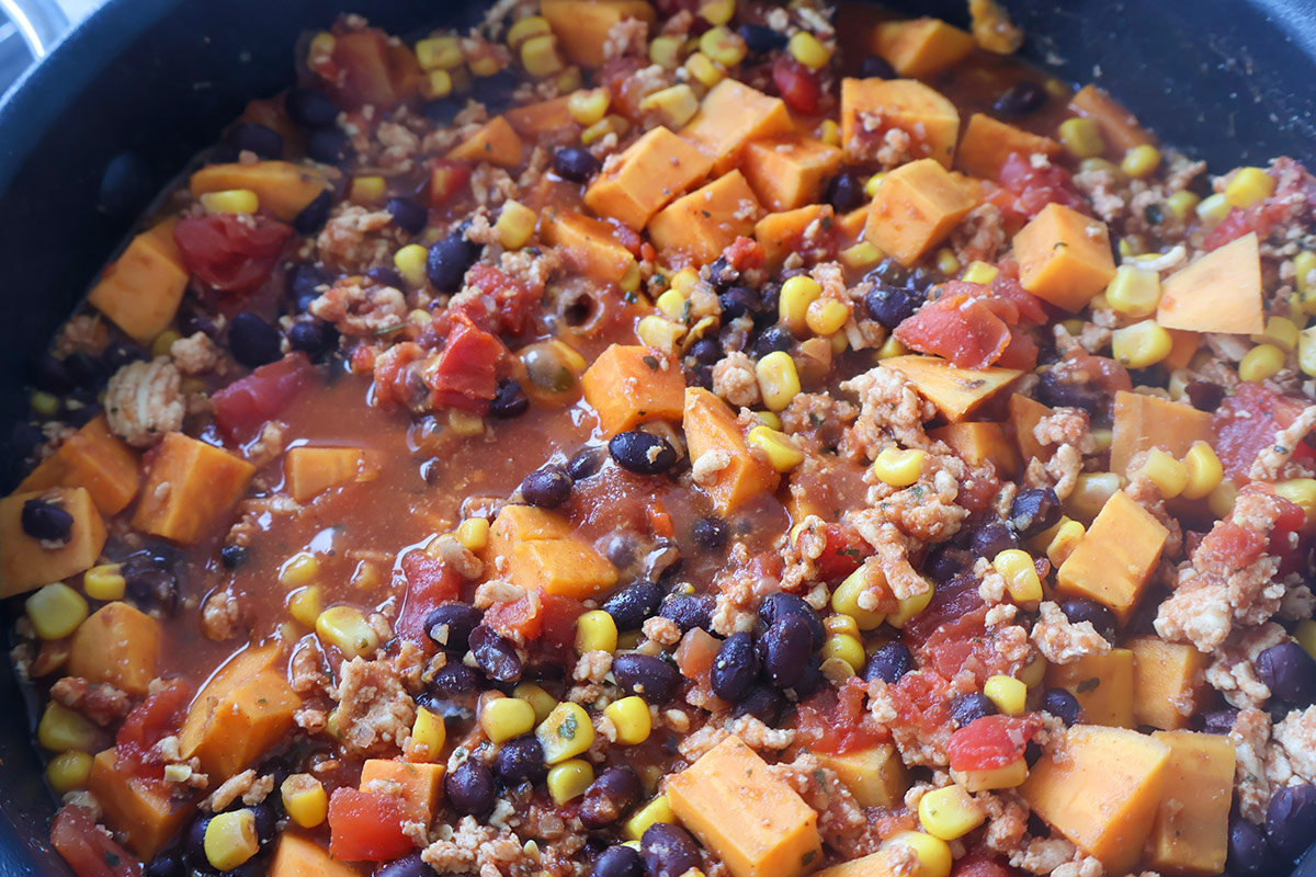 Skillet full of chicken, sweet potatoes, and veggies.