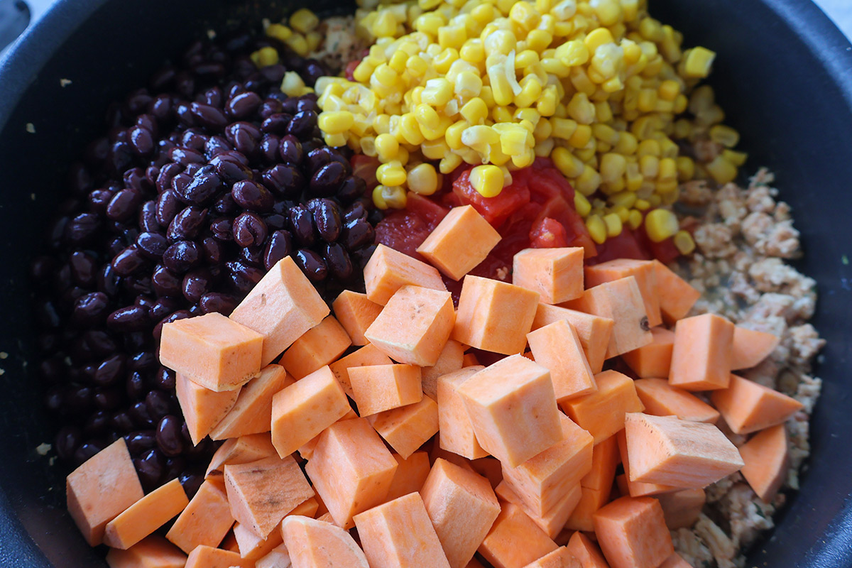 A skillet full of ground chicken, sweet potatoes, and veggies.