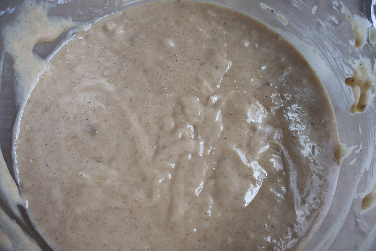A glass mixing bowl filled with banana cake batter.