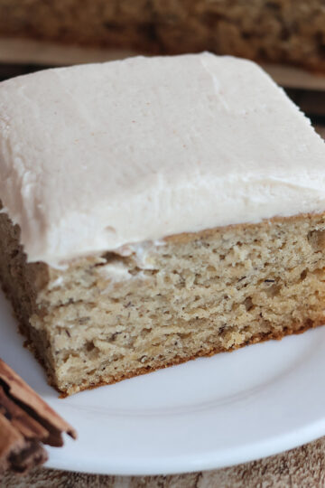 A slice of frosted banana cake on a white plate.