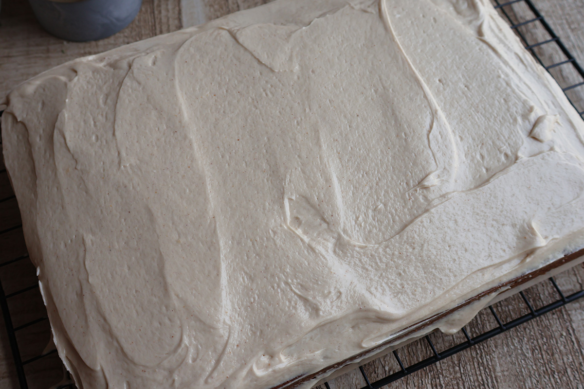 Whole frosted banana cake on a wire cooling rack.