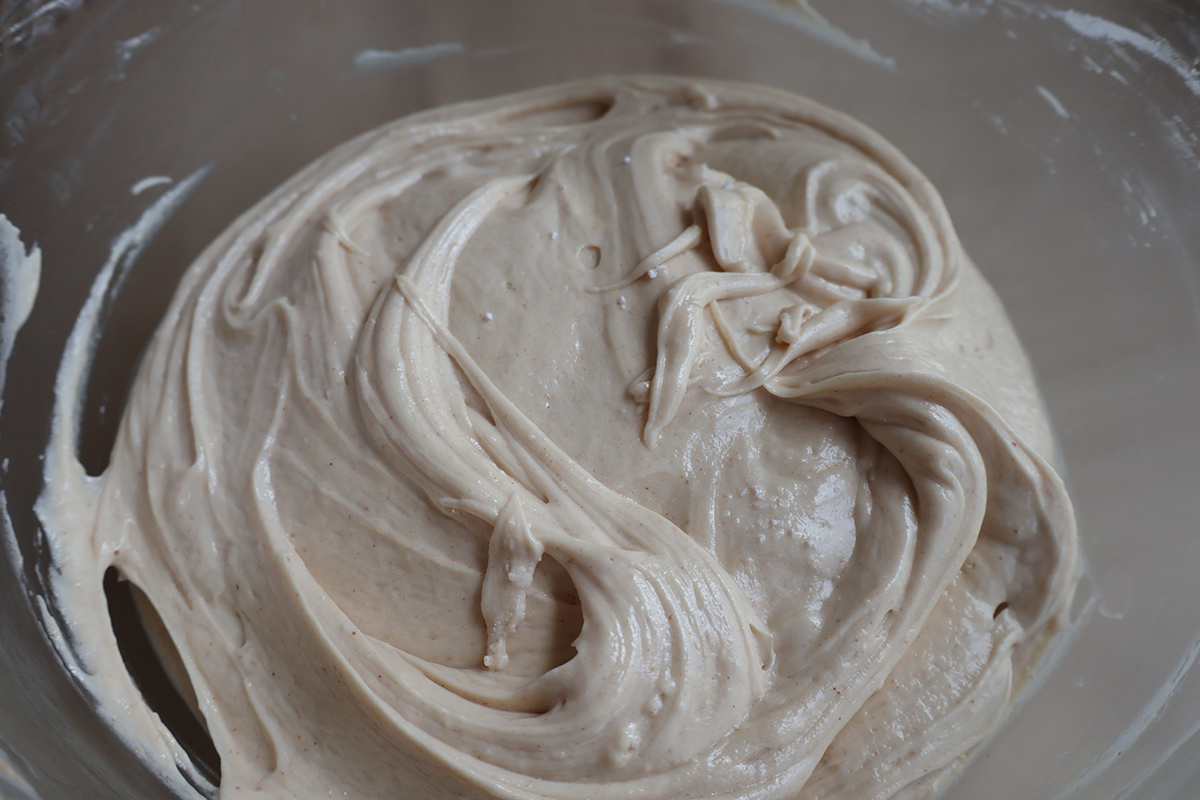 A glass mixing bowl full of peanut butter cream cheese frosting.