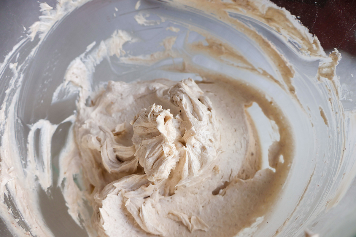 A glass mixing bowl full of cream cheese frosting.