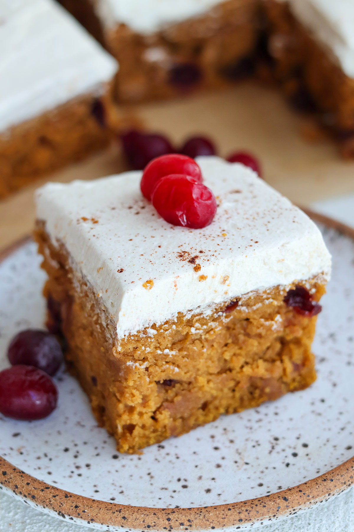 A slice of frosted pumpkin cake on a plate.