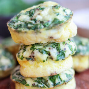 A stack of two egg cups topped with spinach and feta.