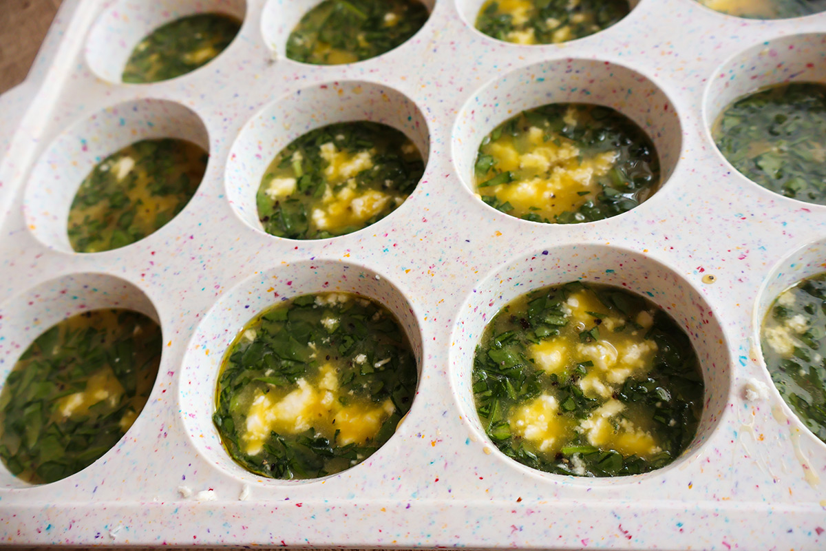 A cupake pan filled with scrambled egg mixture. 