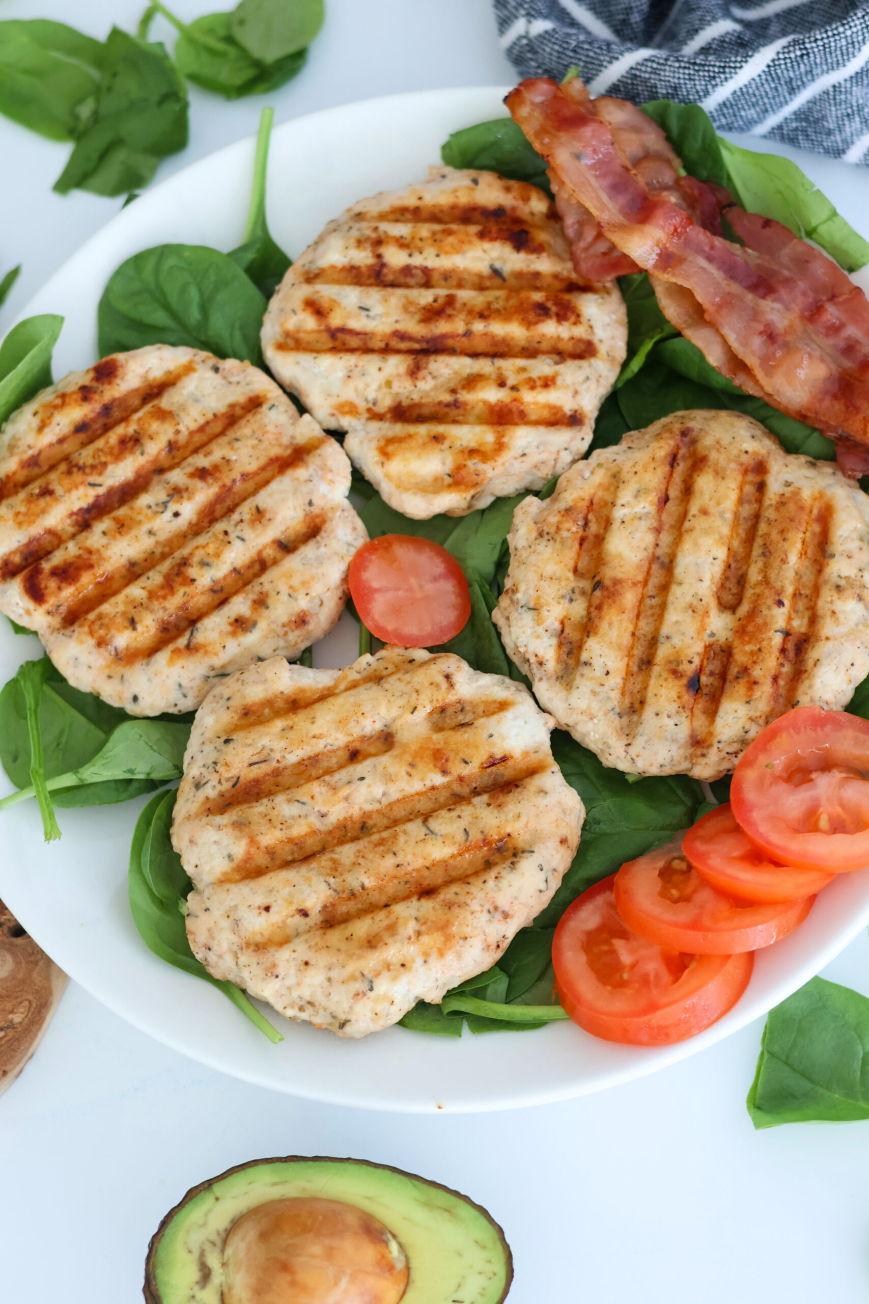 4 grilled chicken burgers on a plate of lettuce.