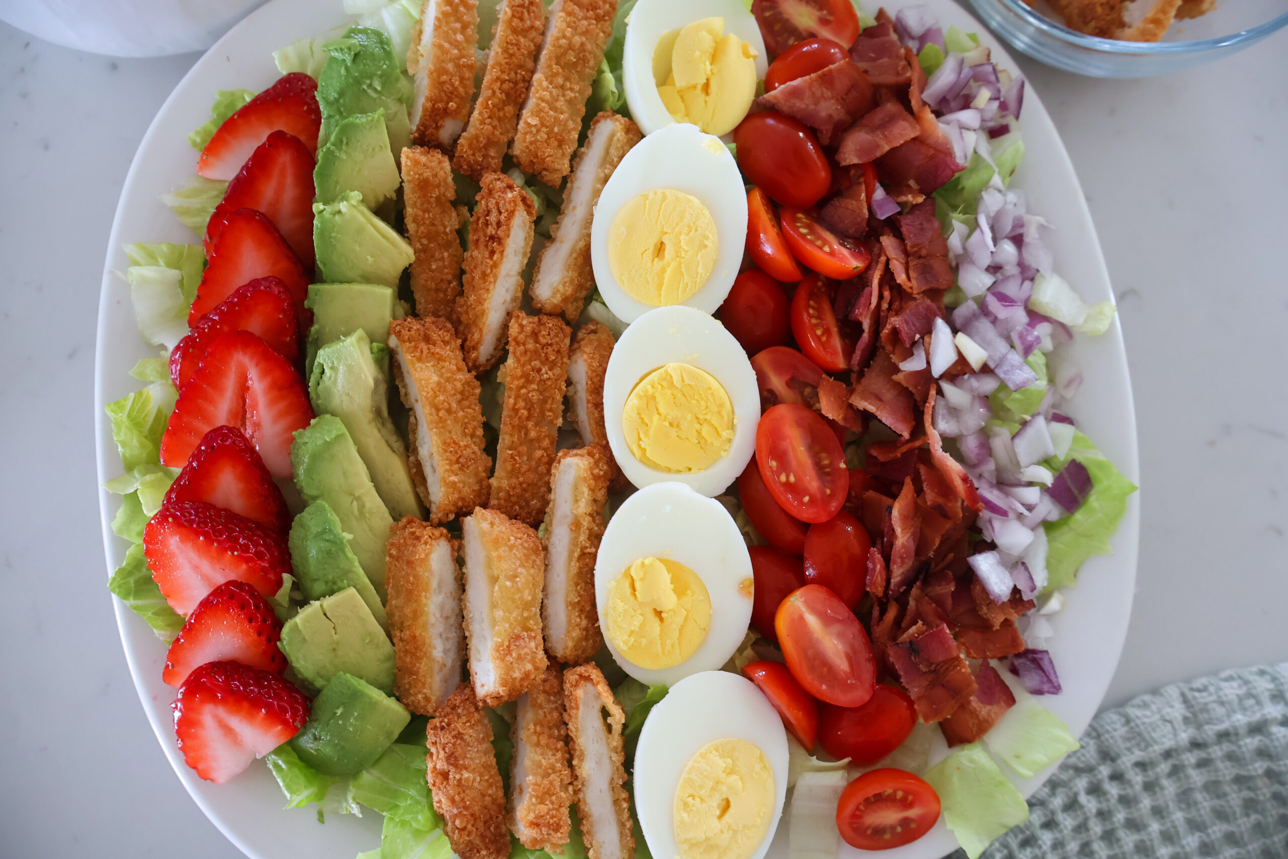Strawberry cobb salad without dressing on a white plate.